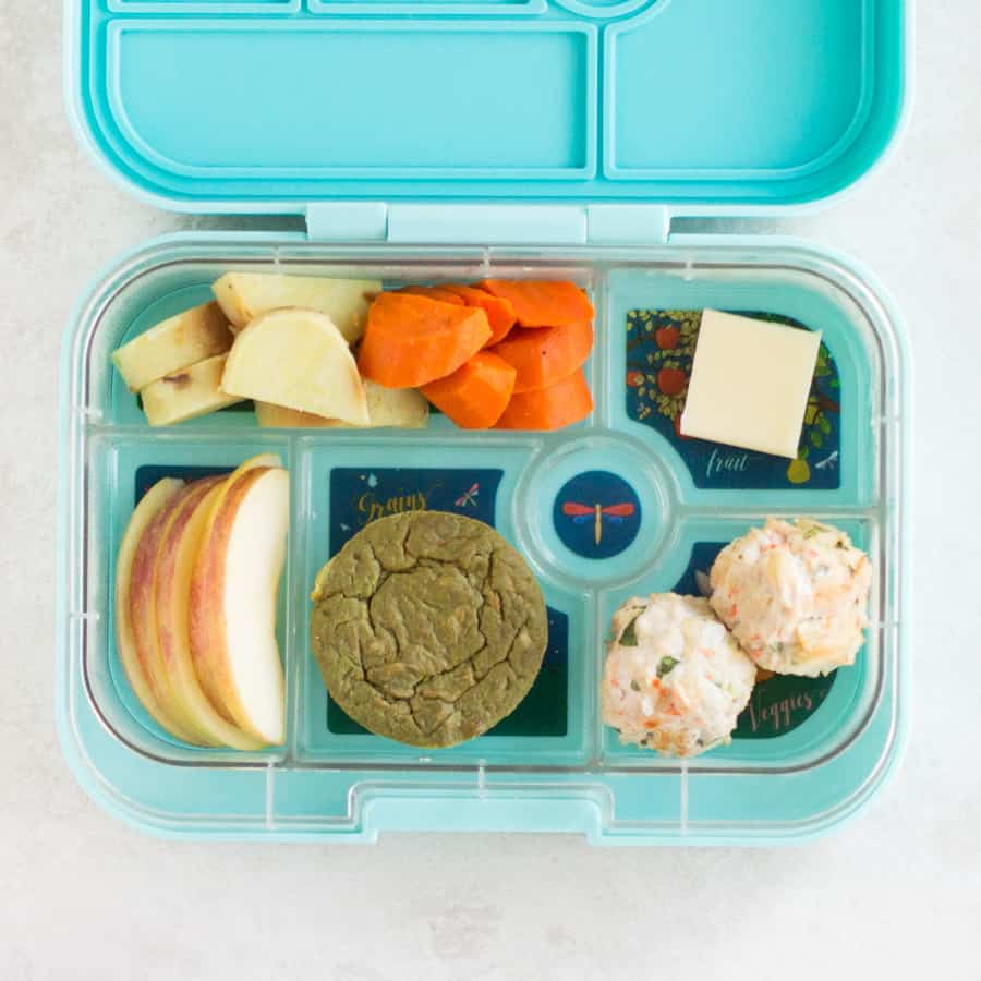 Spinach cake with meatballs, cheese, sweet potatoes, and apples in a lunch box.