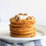 Stacked pancakes with yogurt and pecans.