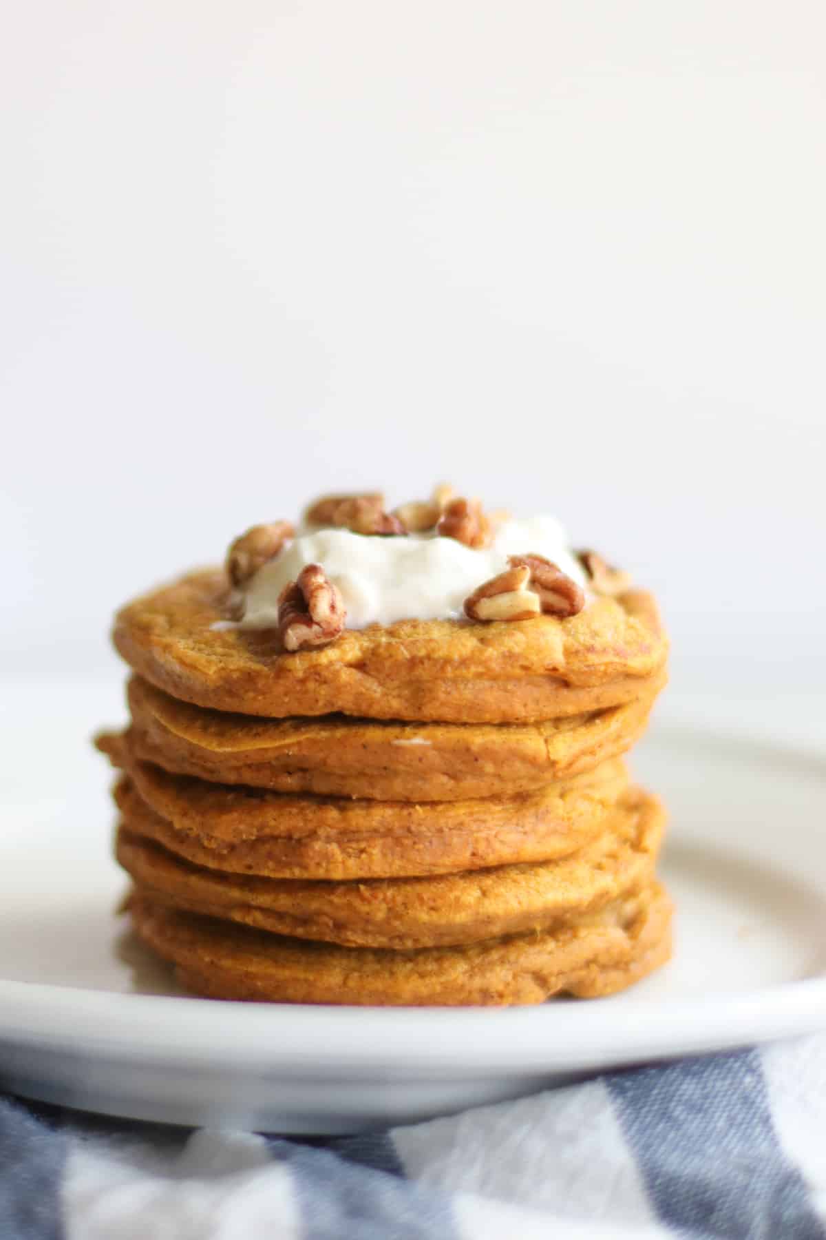 Stacked pancakes with yogurt and pecans.