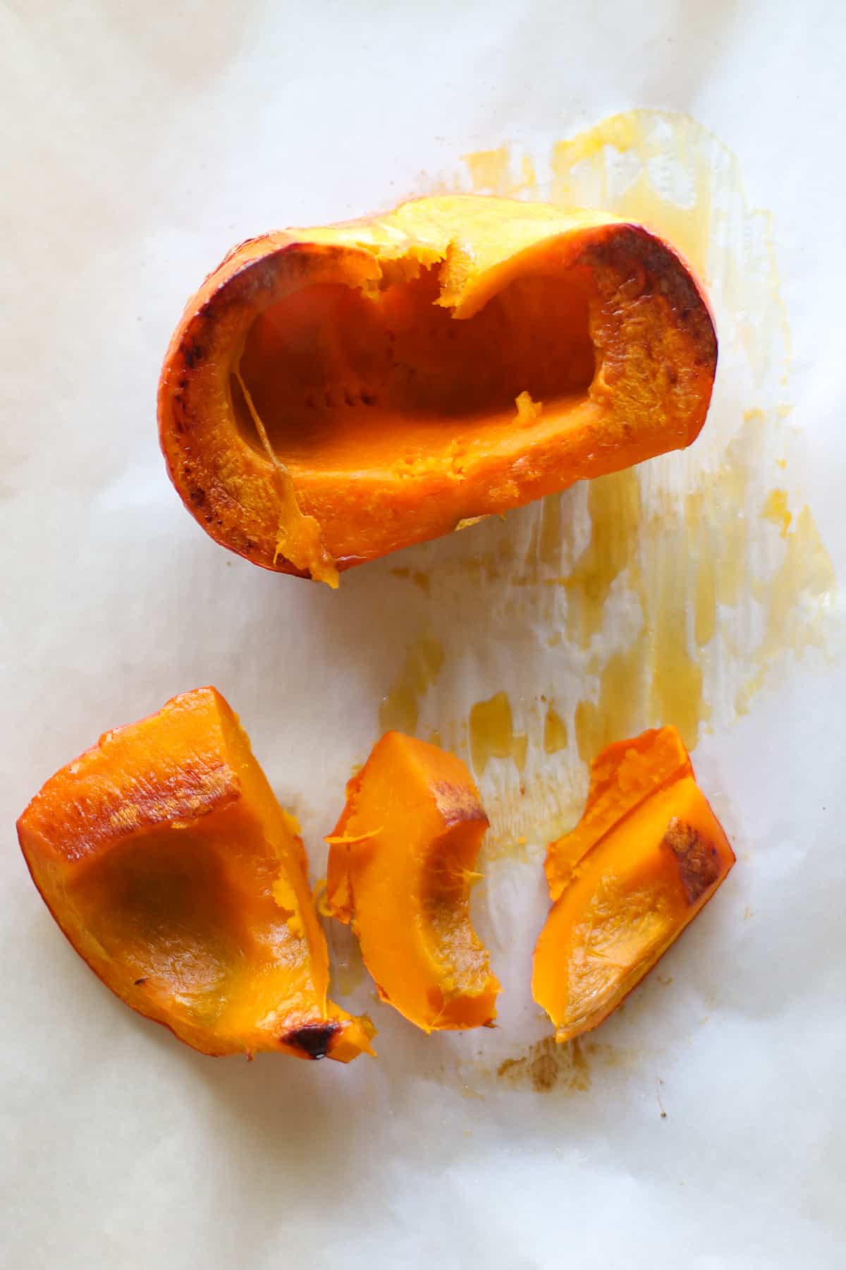 Halved and sliced roasted pumpkin on a baking sheet.