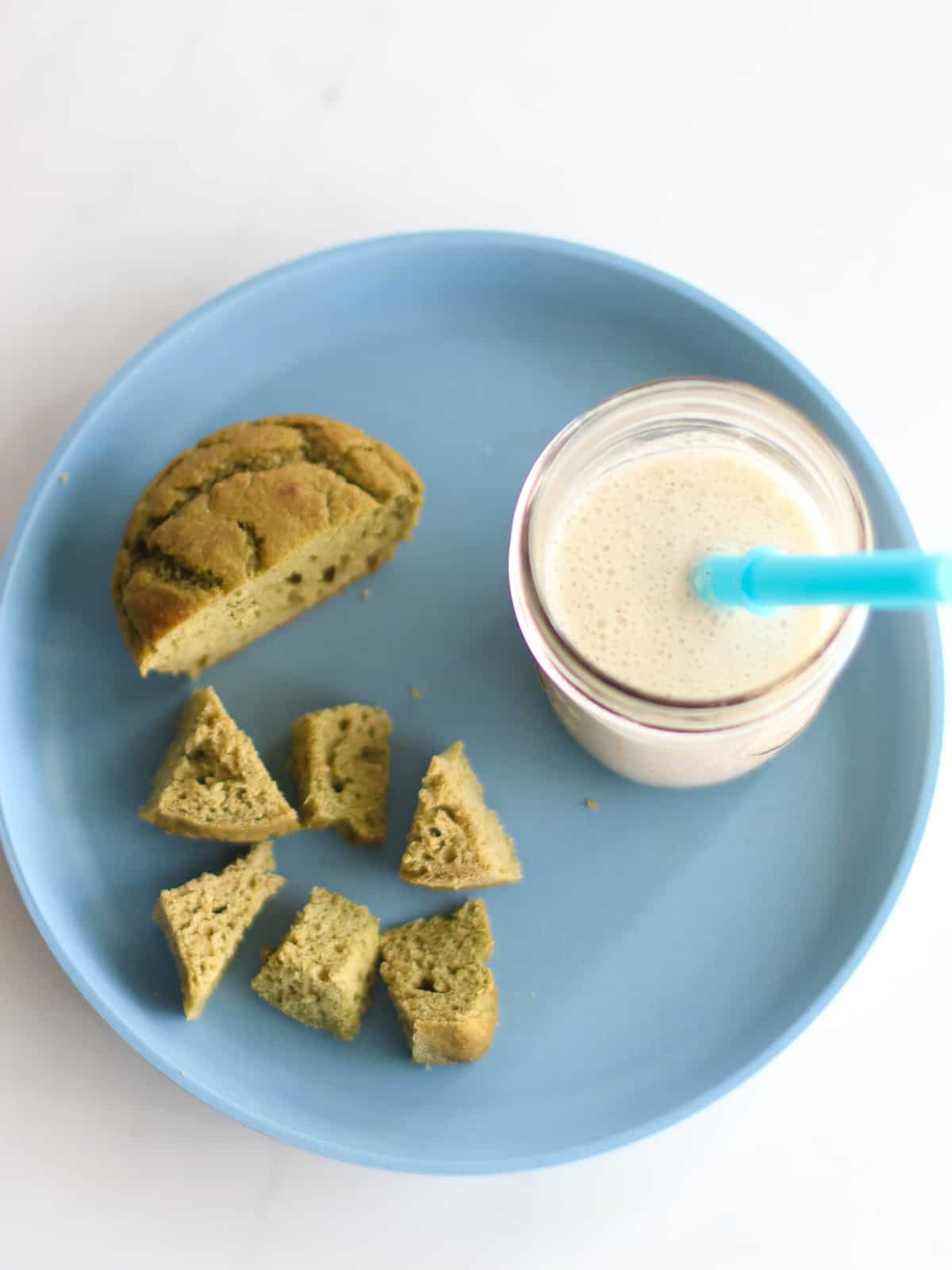 Banana milk with spinach muffin on a blue plate.