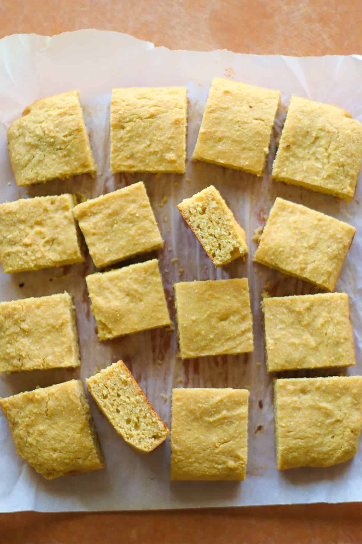 Baked and sliced cornbread on a wooden board.
