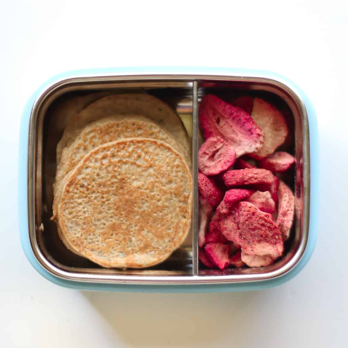 3 pancakes with freeze-dried strawberries in a container.