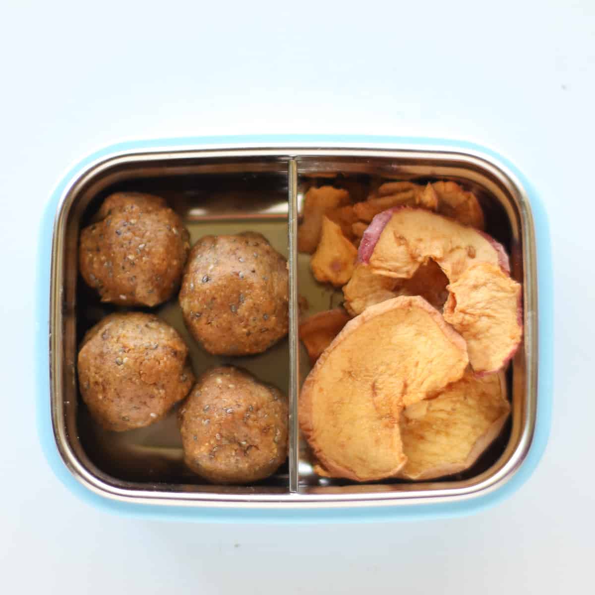 Pumpkin balls with apple chips in a snack container.