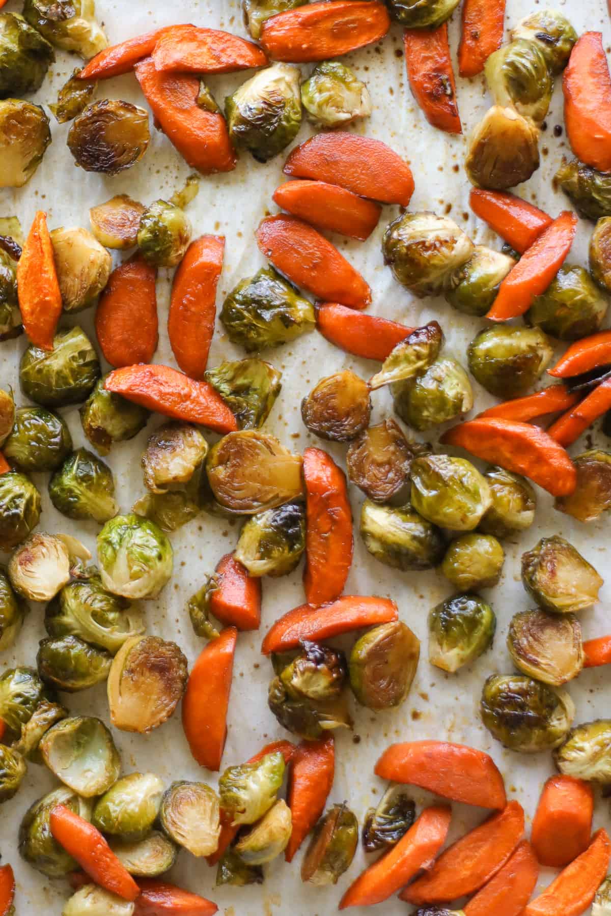 Roasted vegetables in a lined baking sheet.