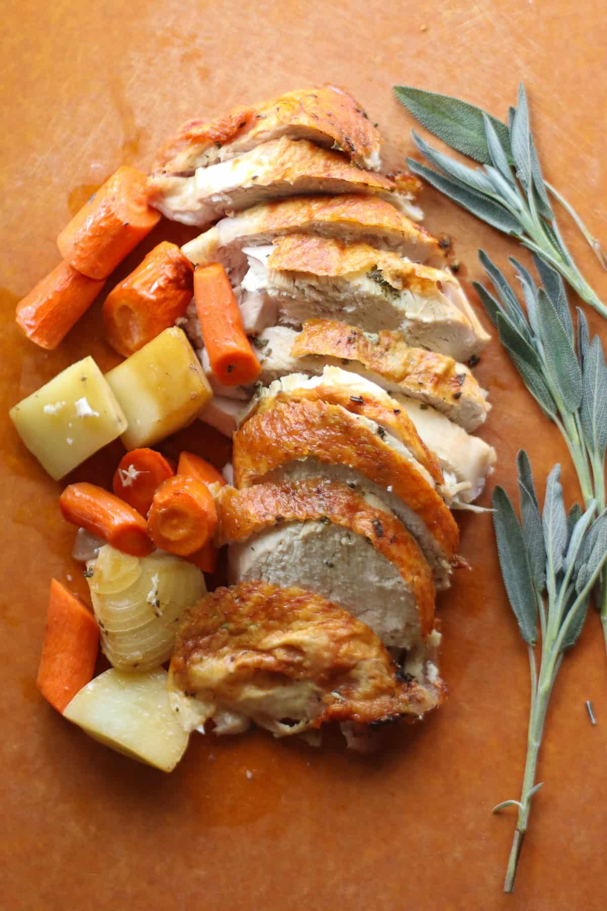 Sliced roasted turkey breast with vegetables and fresh sage.