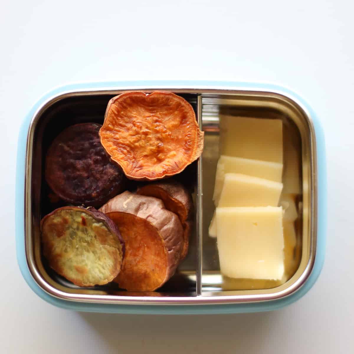 Sweet potatoes and cheese in a stainless steel snack container.