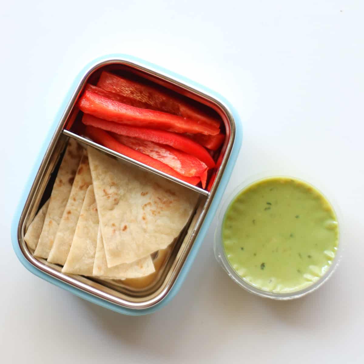 Tortilla and bell peppers in a snack container with a side of guacamole.