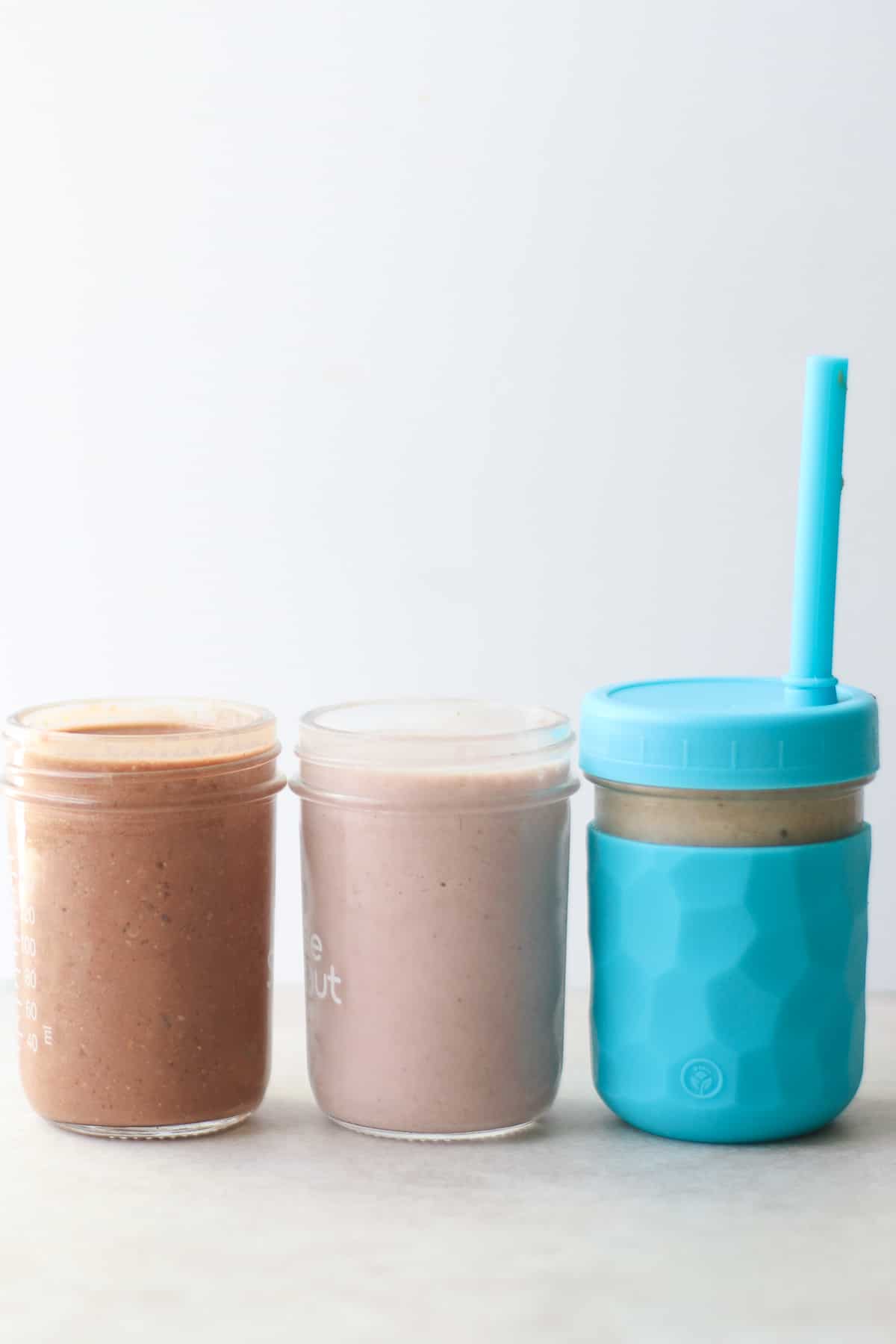 3 banana milkshake flavors in glass jars and a straw for one on the right.