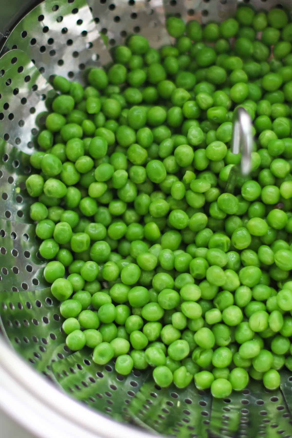 Steamed frozen peas in a steamer basket.