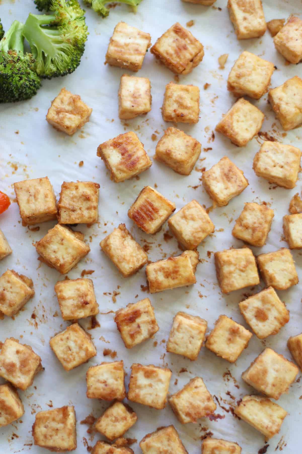 Freshly baked tofu on a parchment lined baking sheet.