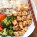 A close up shot of miso tofu in a bowl with rice and vegetables.