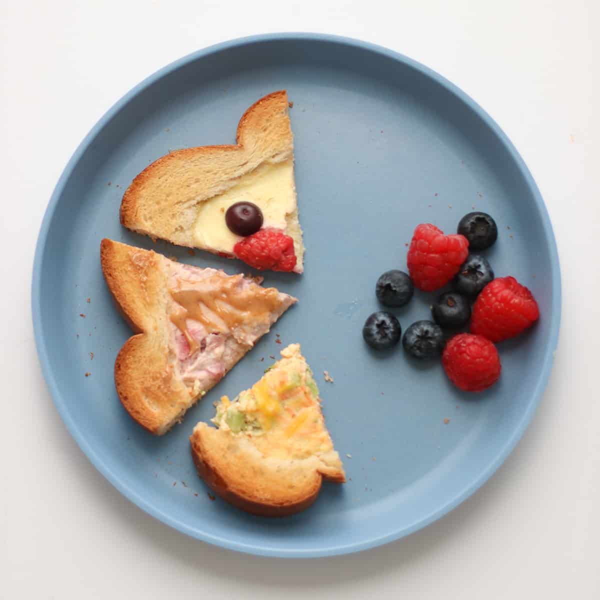 A toddler's plate with toast cut into three triangles with berries on the side.