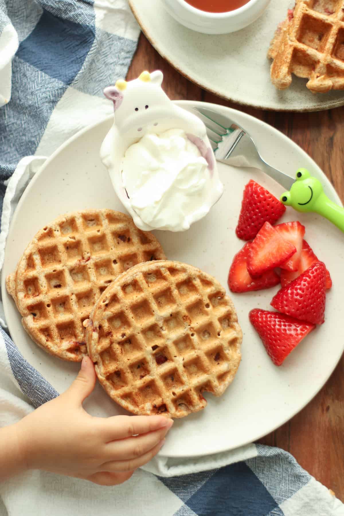 Two waffles with yogurt and fresh strawberries.