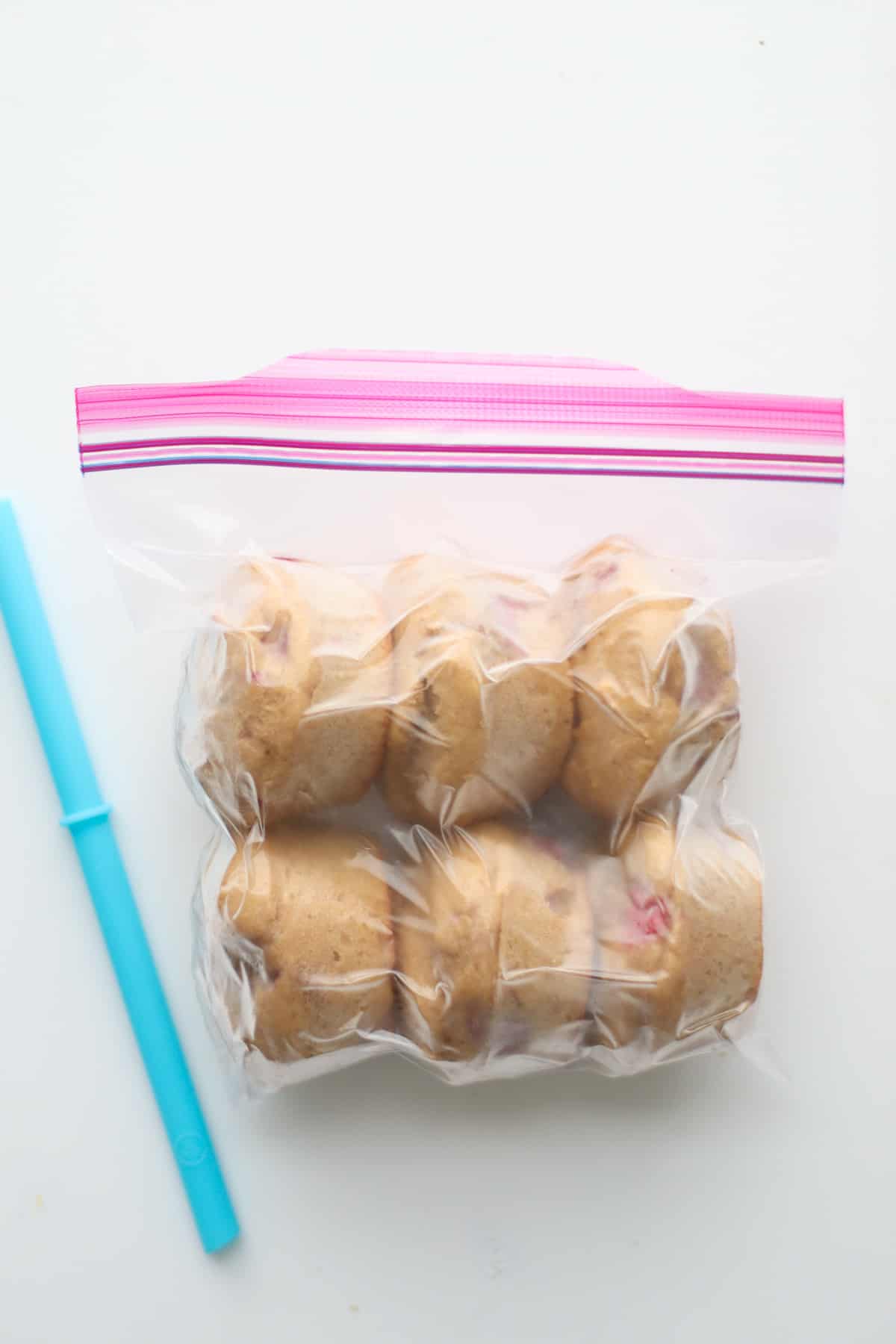 Six muffins in plastic bag with air sucked out with straw.