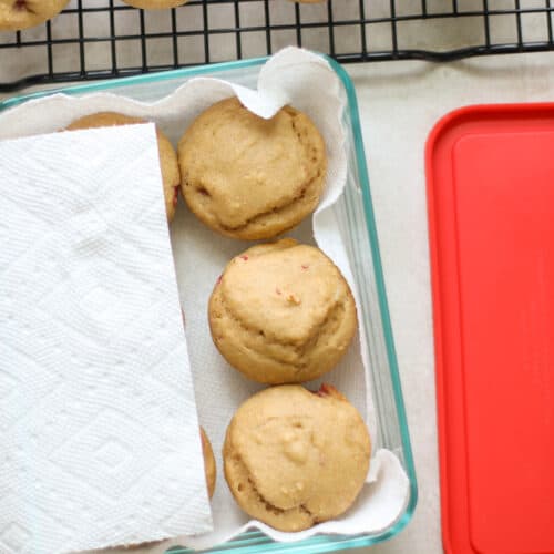 Muffins in glass container lined with paper towels.