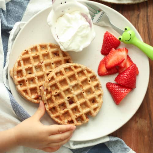 Two waffles with yogurt and fresh strawberries.