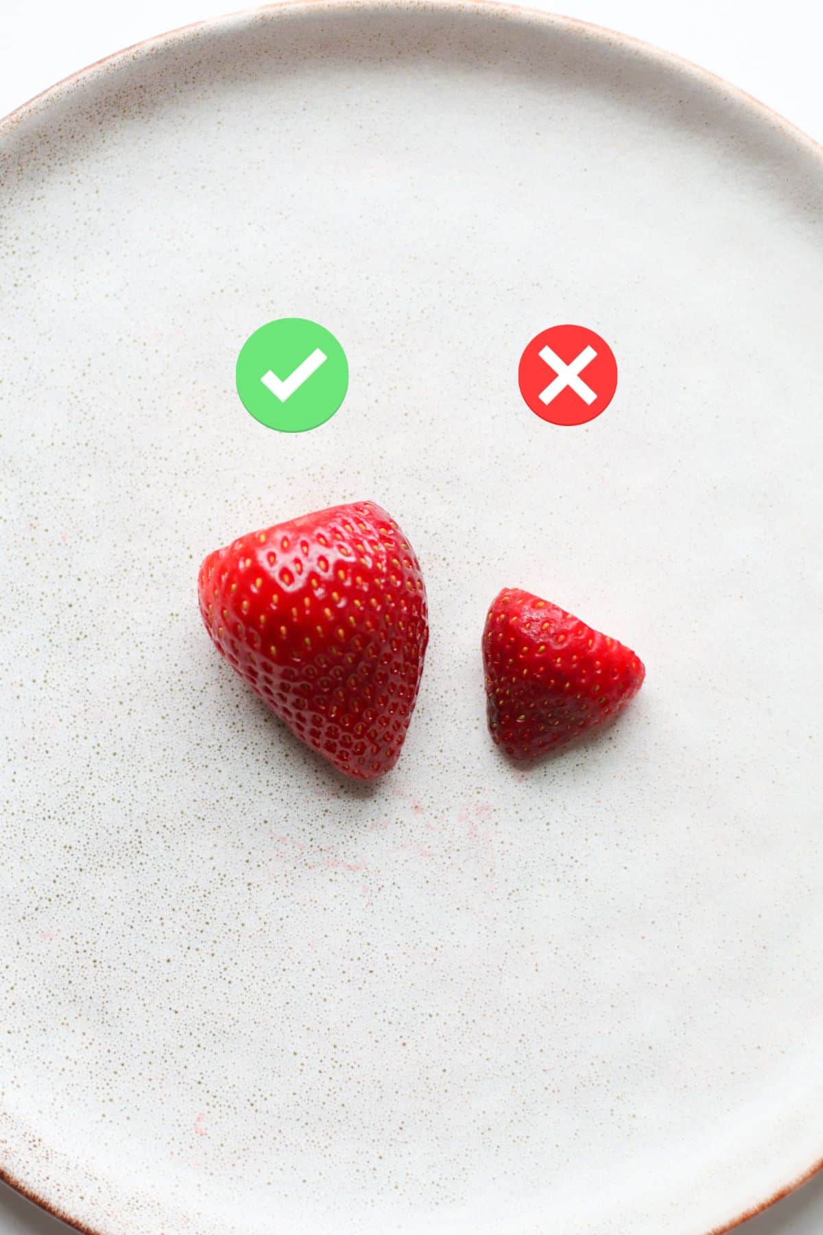 A large strawberry with a checkmark and a small strawberry with an X.