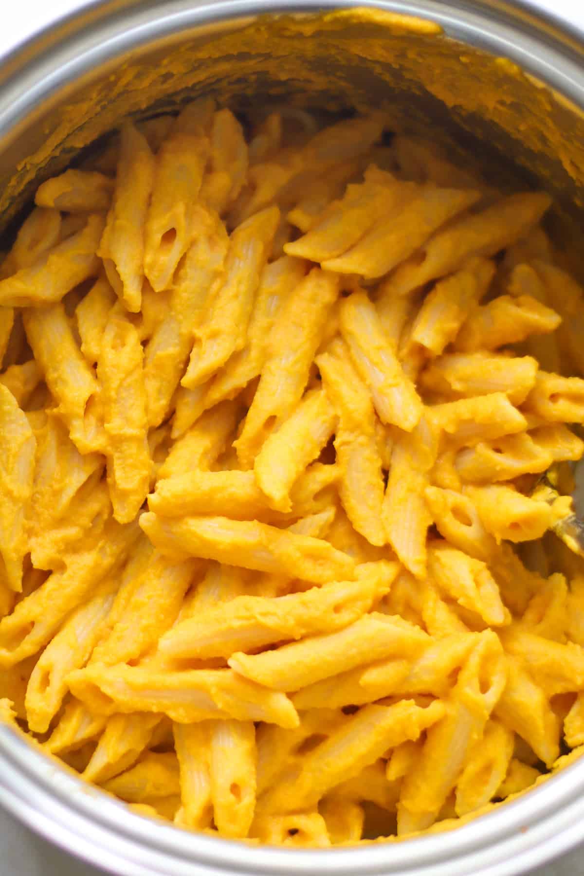 A close up shot of carrot pasta in a large pot.