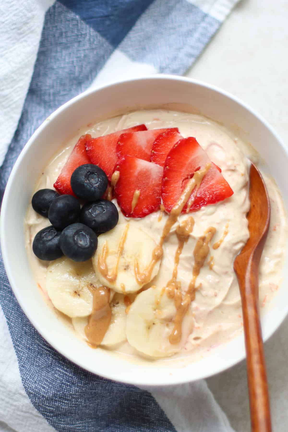 peanut butter yogurt with banana, blueberries, strawberries, and a drizzle of peanut butter.