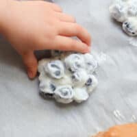 Frozen yogurt covered blueberries with toddler's hand.