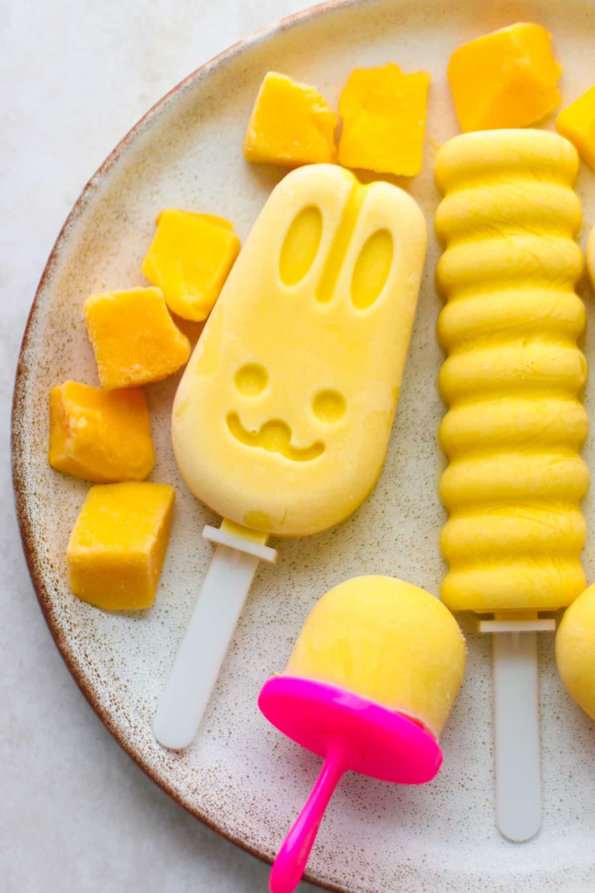 A close up shot of fun shaped popsicles on a white plate.