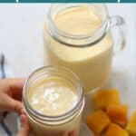 a slightly angled shot of mango shake in two glass jars with toddler holding one.