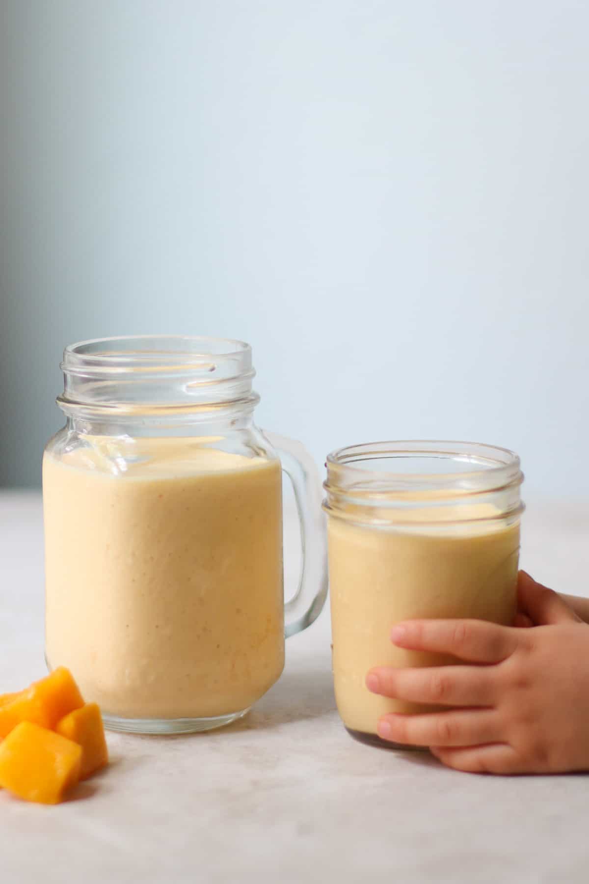 Shake in a large and small glass jars with toddler's hand wrapped around one.