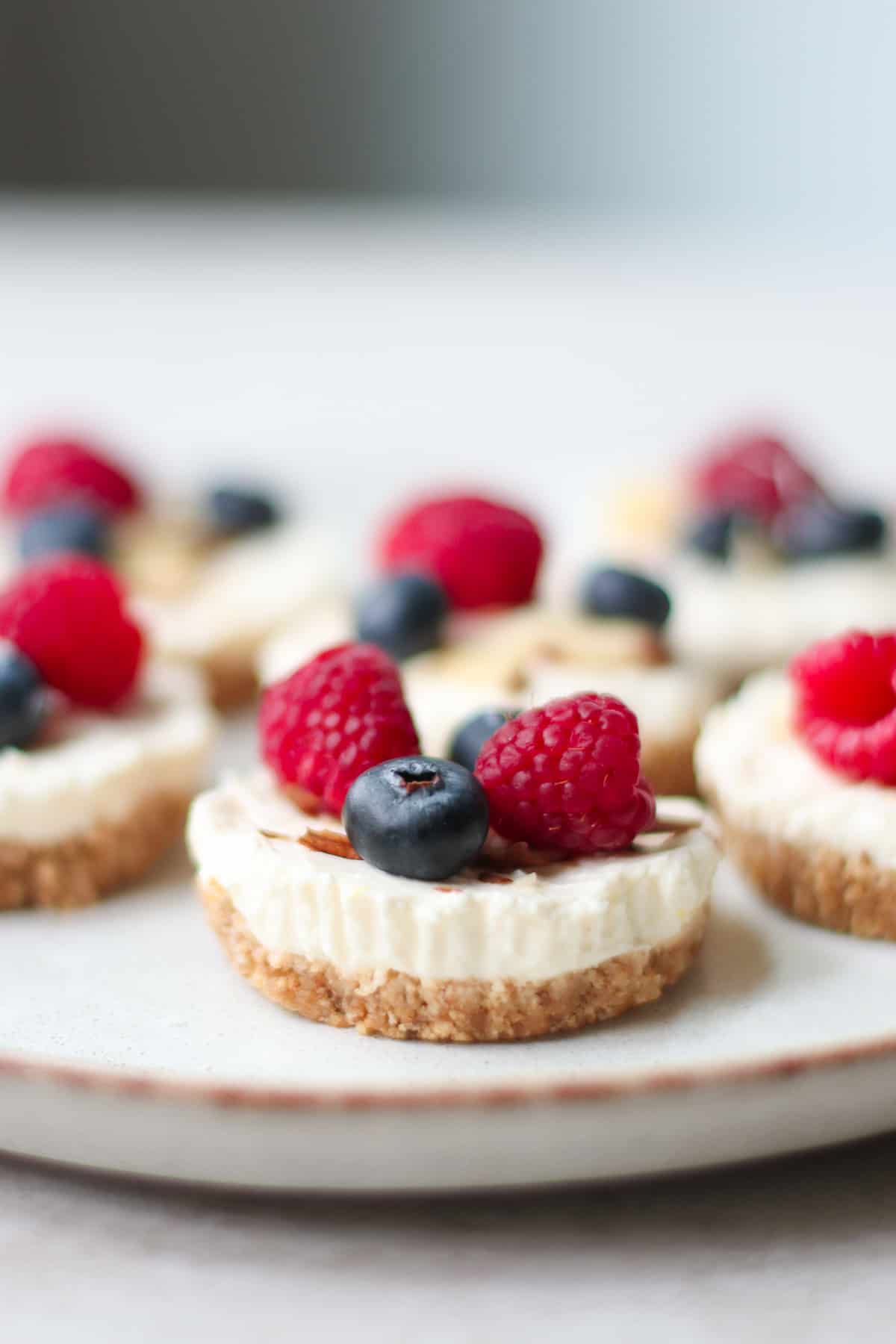 A close up shot of mini cheesecake topped with berries and sliced almonds.