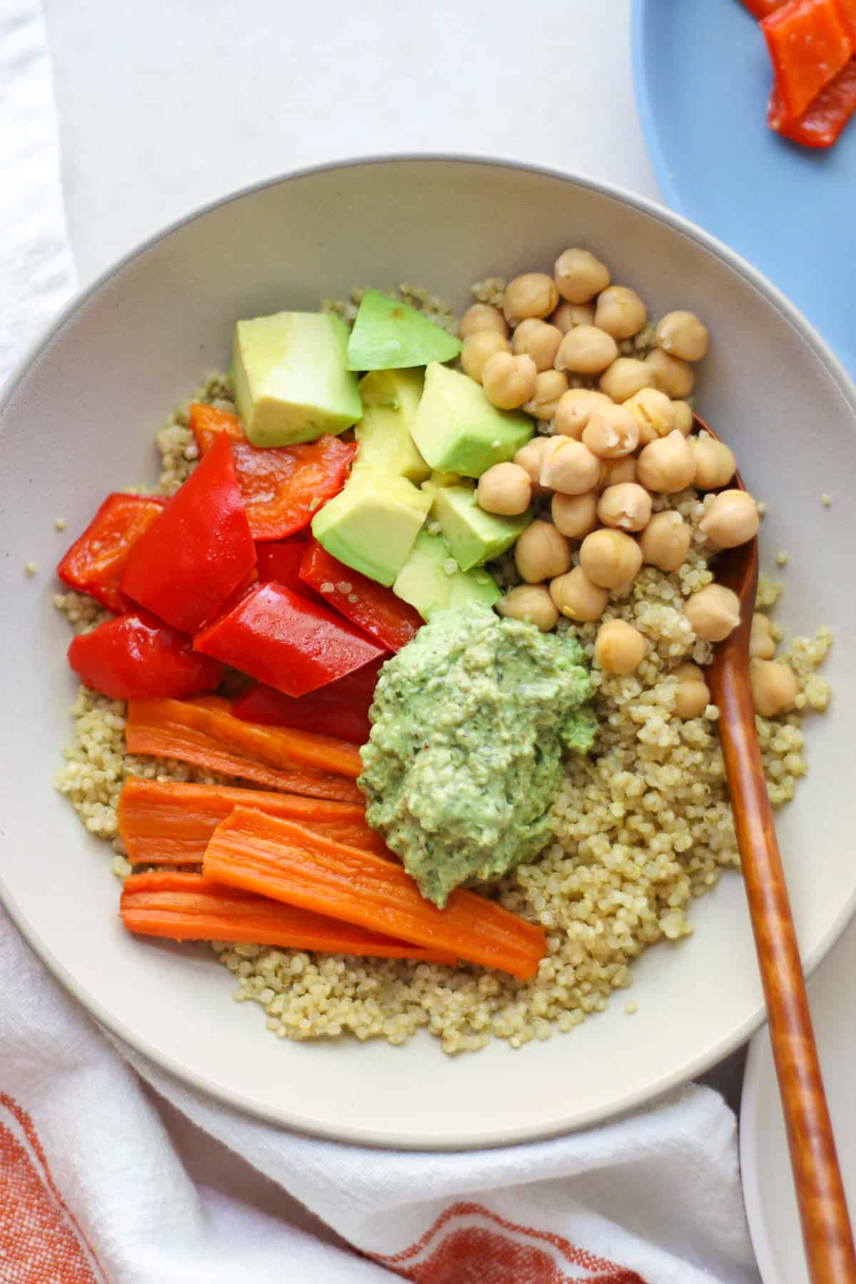 Quinoa bowl with carrots, bell peppers, ricotta pesto, avocado, and chickpeas.