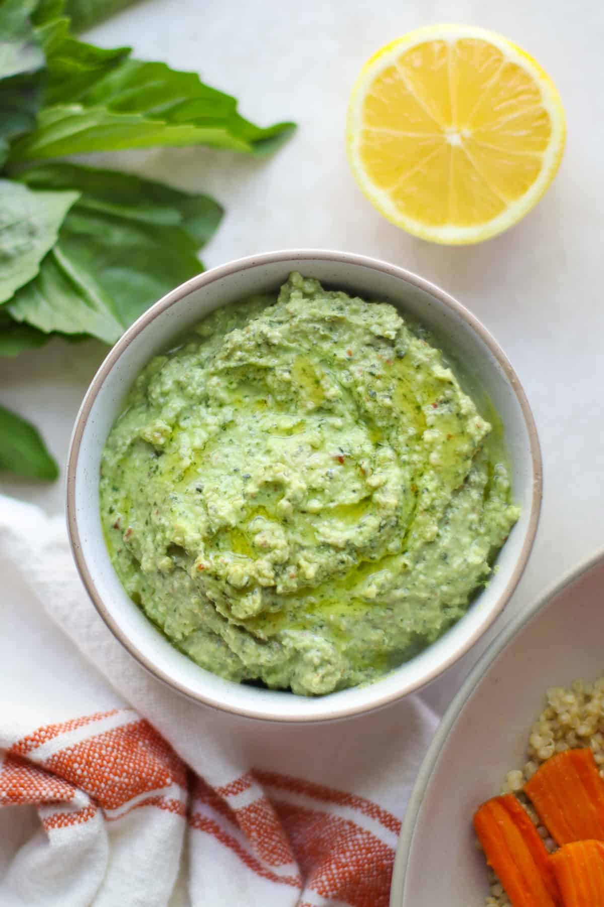 Overhead shot of ricotta pesto in a bowl with lemon and basil in the background.