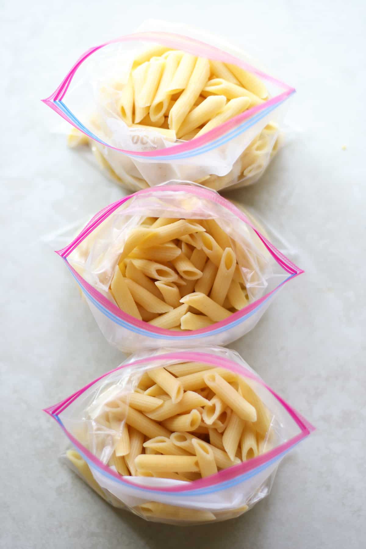 Cooked pasta divided into three freezer-safe bags.