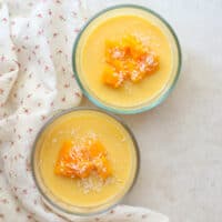 Overhead shot of two mango puddings in glass containers.