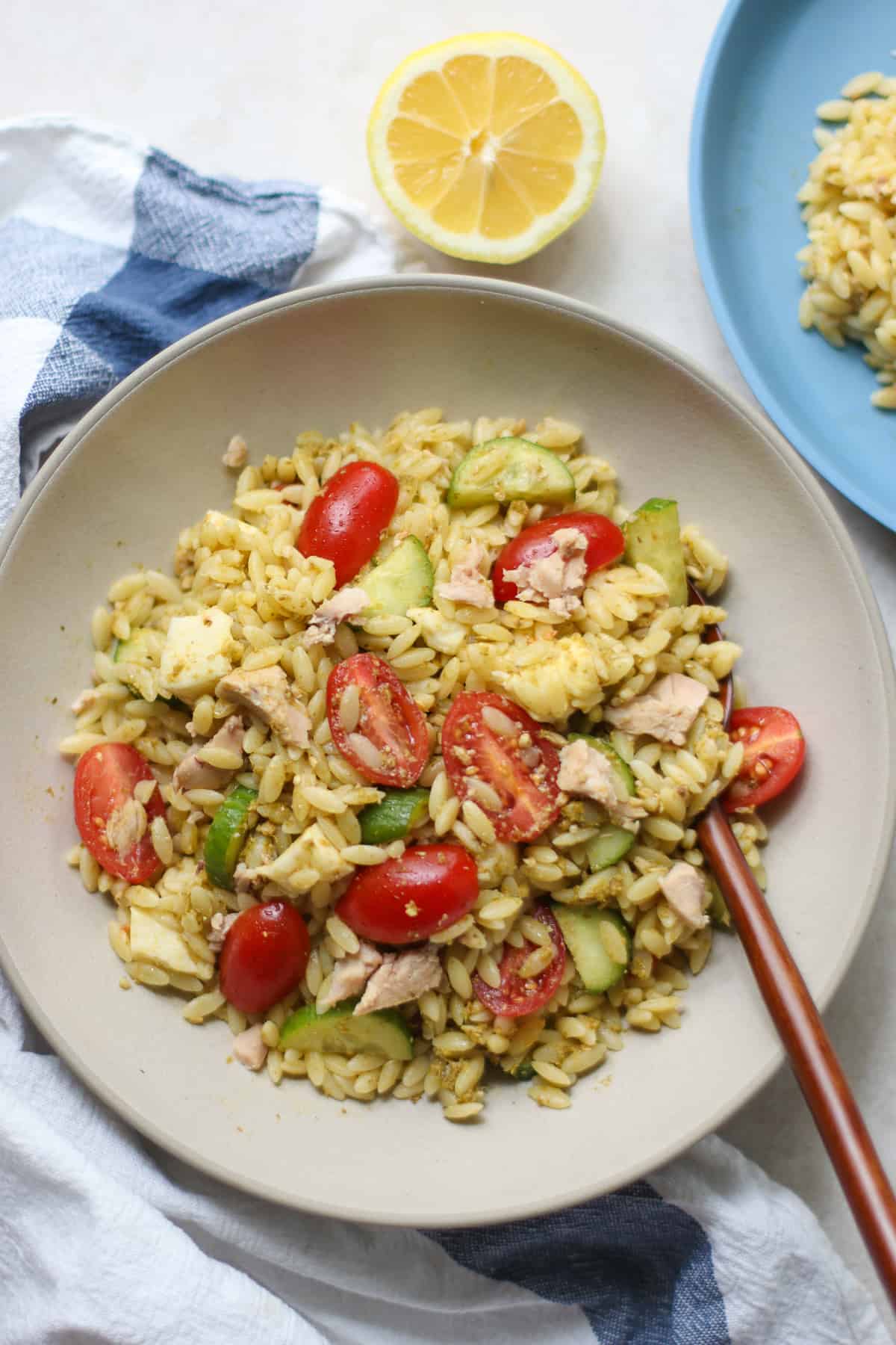 An overhead shot of pesto orzo salad with a wooden spoon.