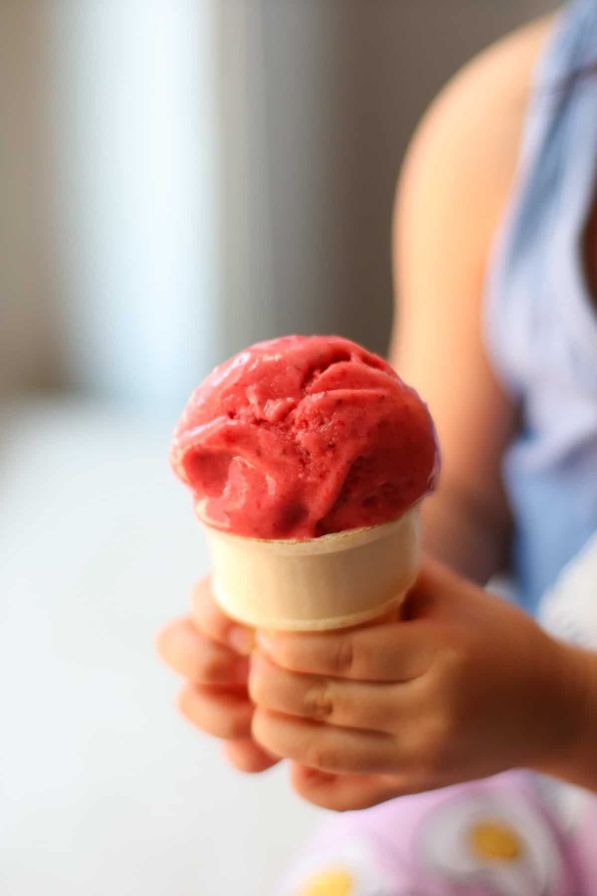 Frozen strawberry sorbet in a cone.