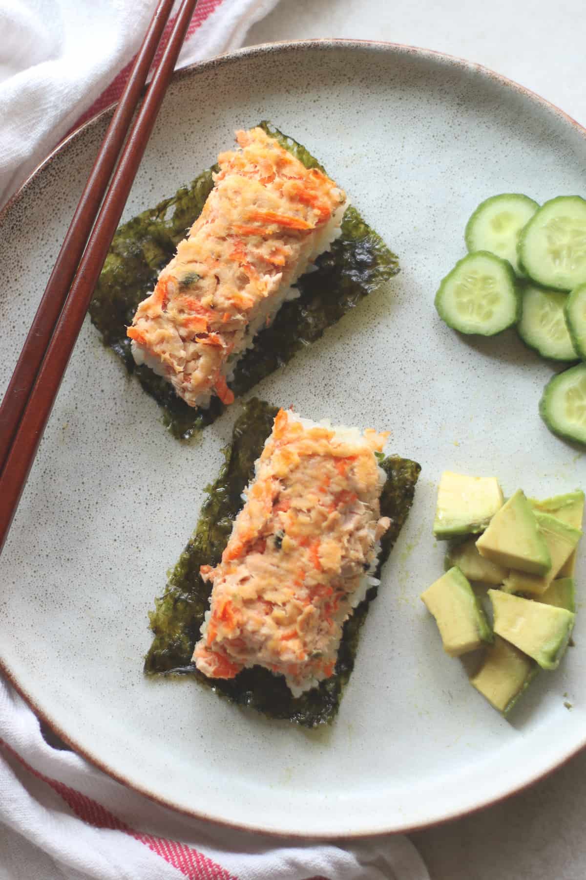 Two individually scooped sushi bake on seaweed sheet with cucumber and avocado on the side.