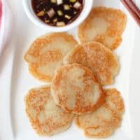 Golden brown gamjajeon with dipping sauce on a white plate.