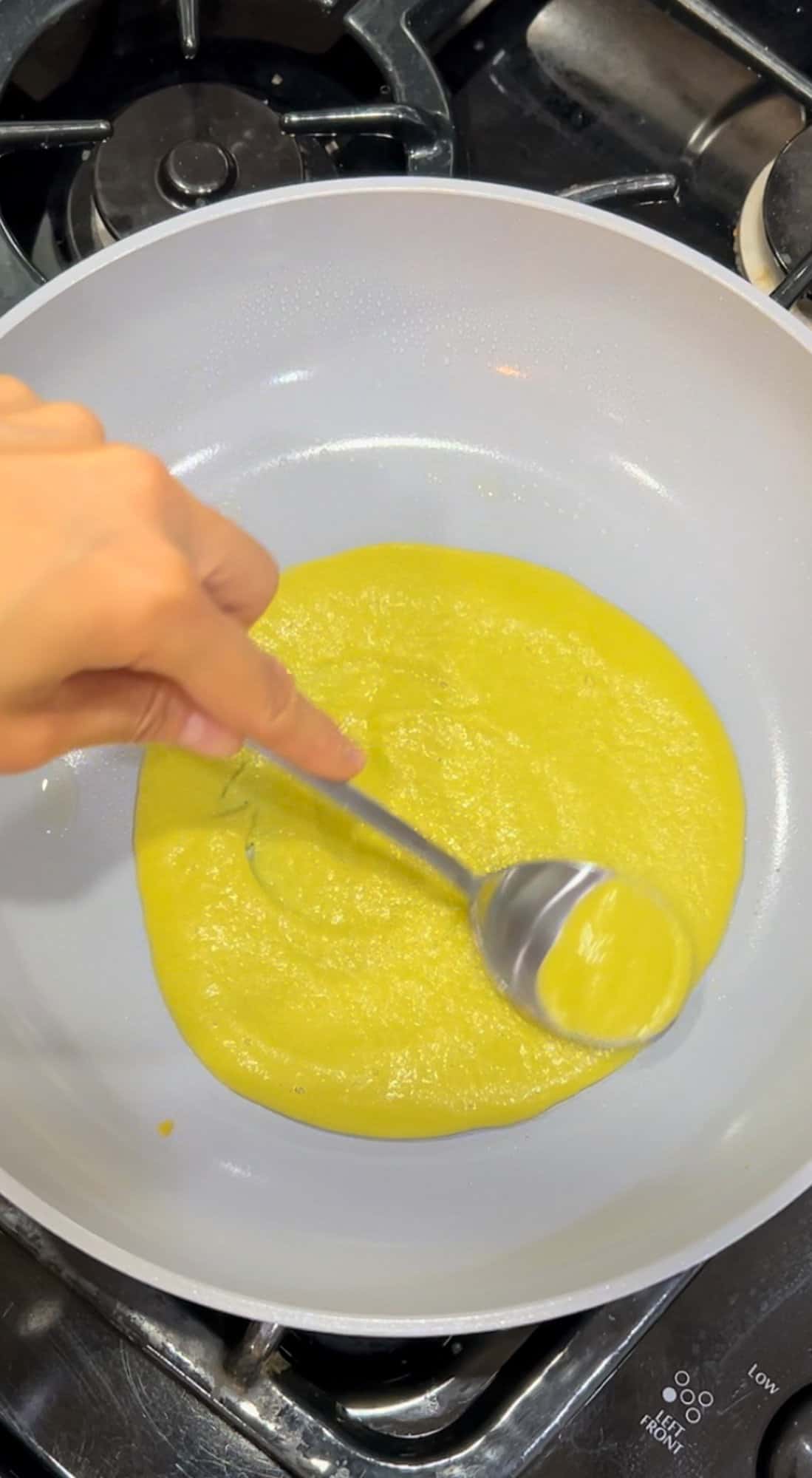 Spreading the wrap batter with the back of a spoon in a pan.