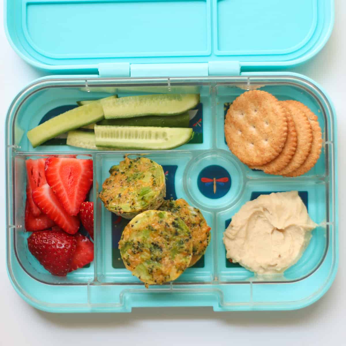 Broccoli bites with crackers, hummus, cucumber, and strawberries.