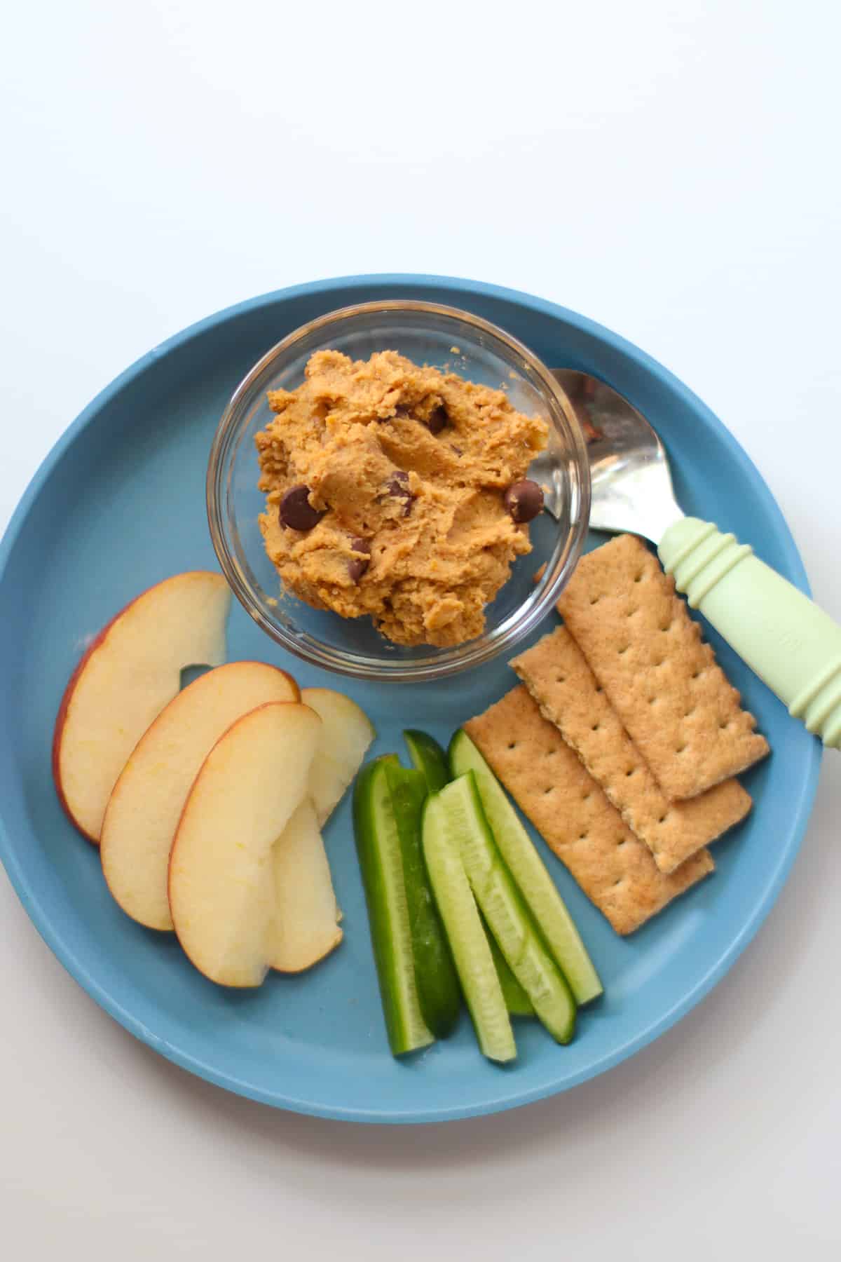 A snack plate with the chickpea cookie dough, apples, cucumber, and graham crackers.