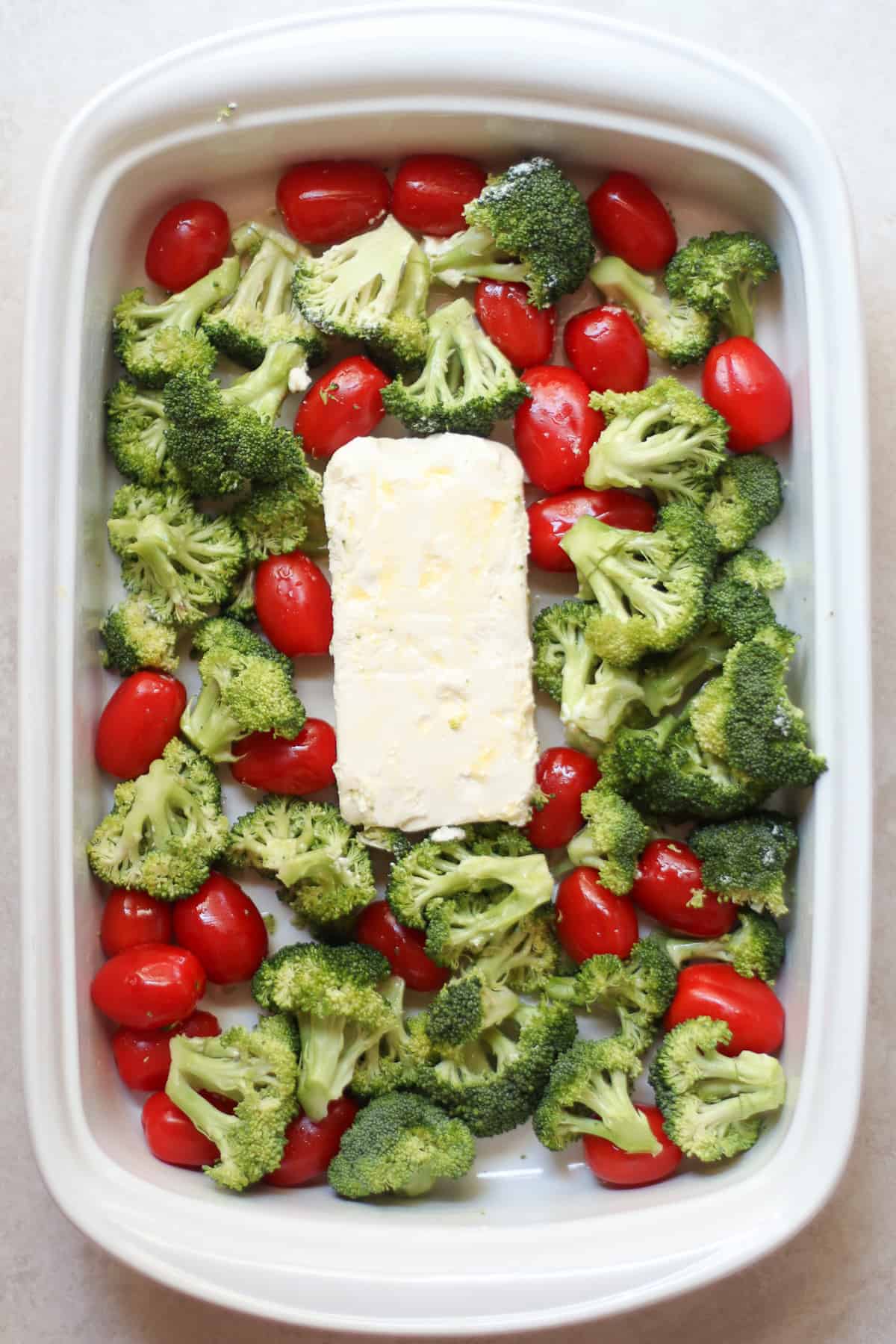Broccoli, tomatoes, and cream cheese in a baking dish.