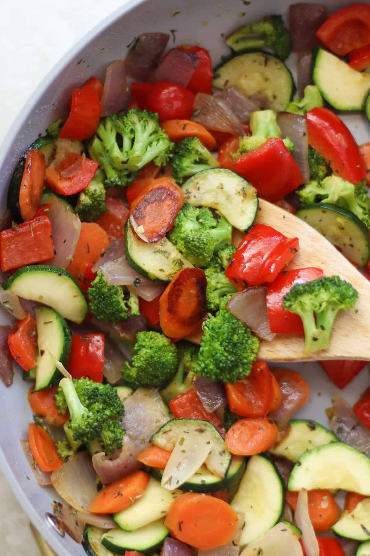 Colorful vegetables scooped with a wooden spoon.