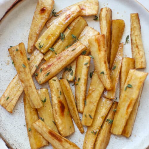 An overhead shot of crispy and shiny parsnips with thyme.