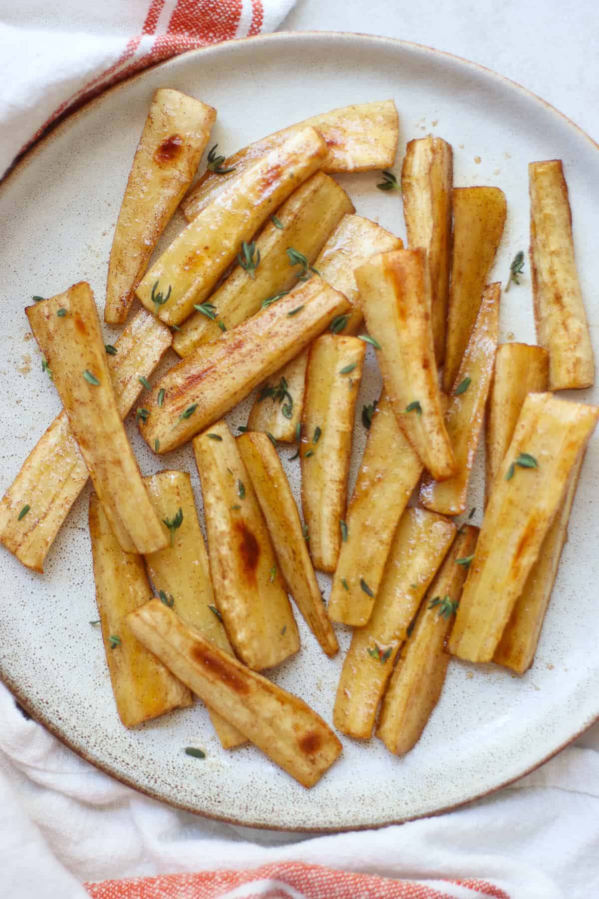 An overhead shot of crispy and shiny parsnips with thyme.