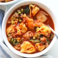 Cooked tortellini soup in a white bowl.