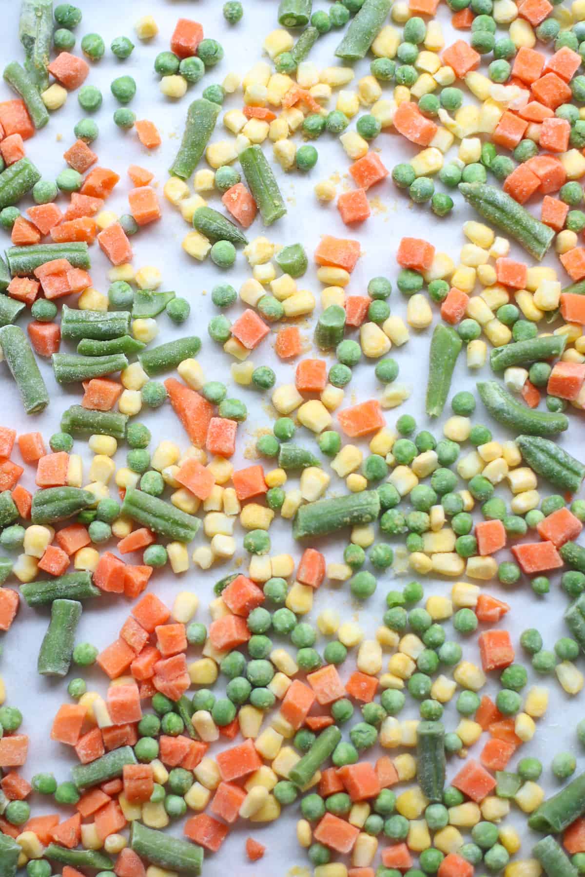 precooked frozen veggies spread out on a baking sheet.