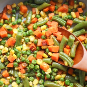 Sauteed frozen mixed veggies in a large pan.