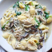Chicken and mushrooms with pasta served in a white bowl.
