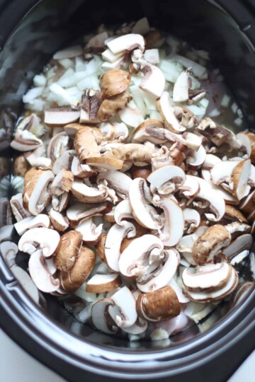 Onion and mushrooms added to slow cooker.