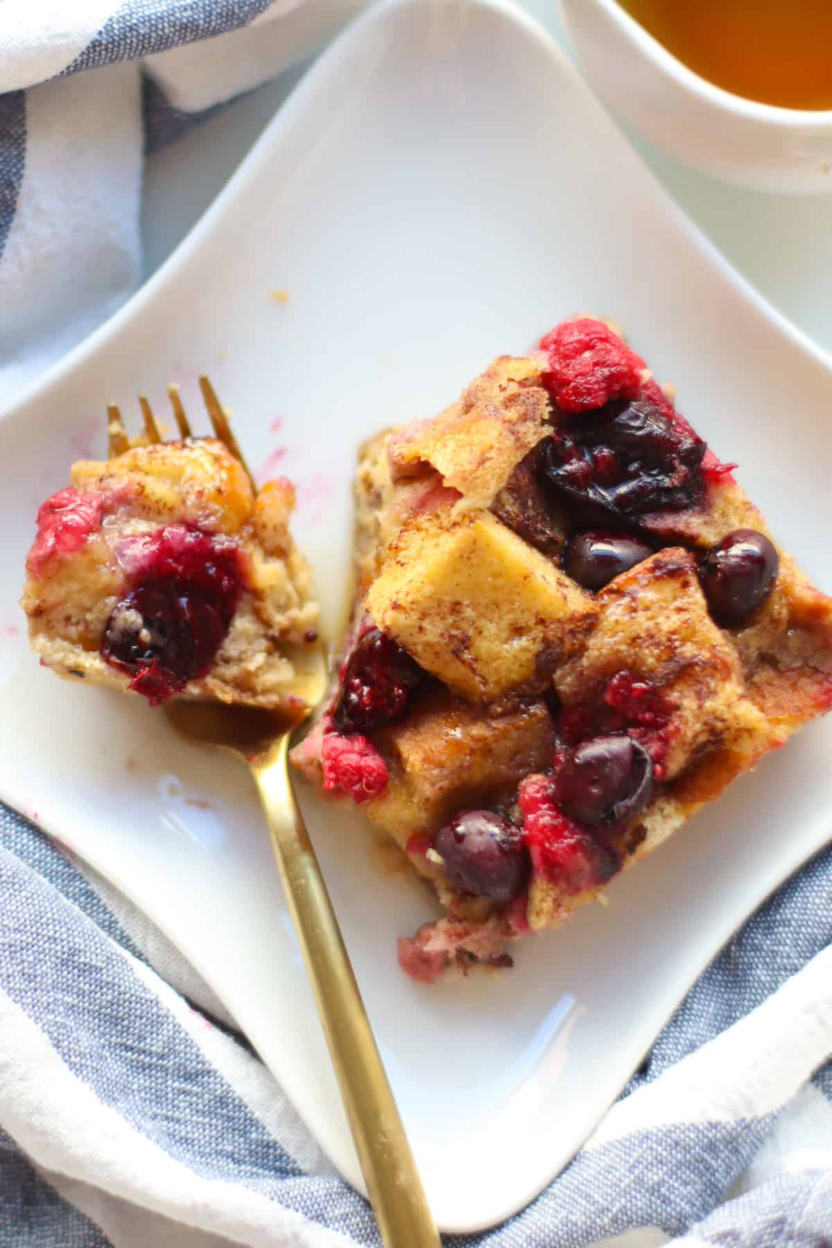 A slice of French toast casserole with a small piece on a fork.